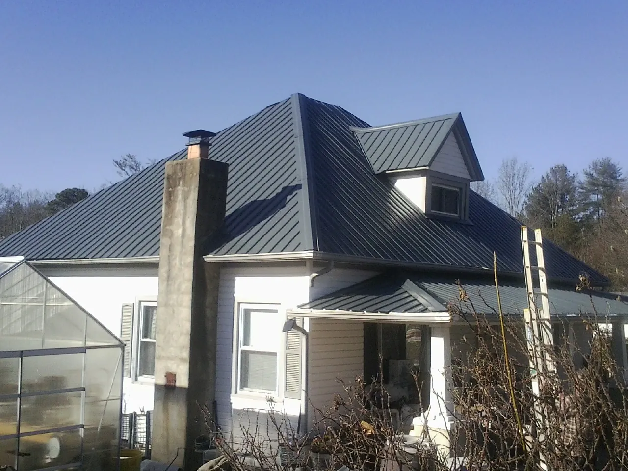 Dark blue standing seam metal roof on a white farmhouse with dormer — Slate & Tile Roof Repair by Roofing Brothers in Lake Katrine