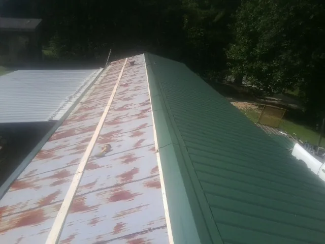 Old rusted panels beside newly installed green metal roofing — Wind Damage Roof Repair by Roofing Brothers in Lake Katrine