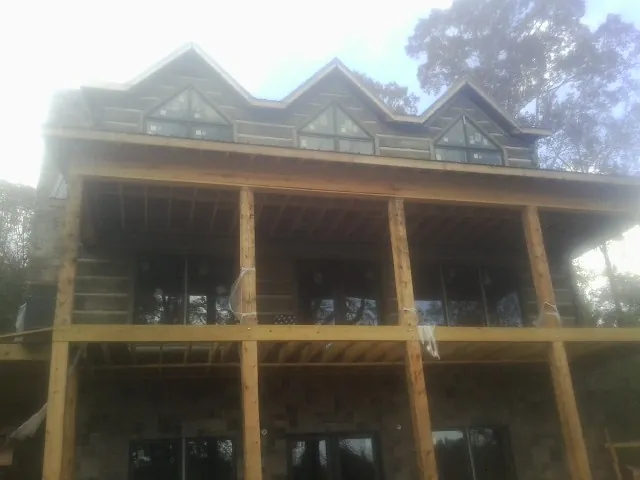 Dormers and porch framing on a large log home under construction — Roof Coating work by our crew in Lake Katrine