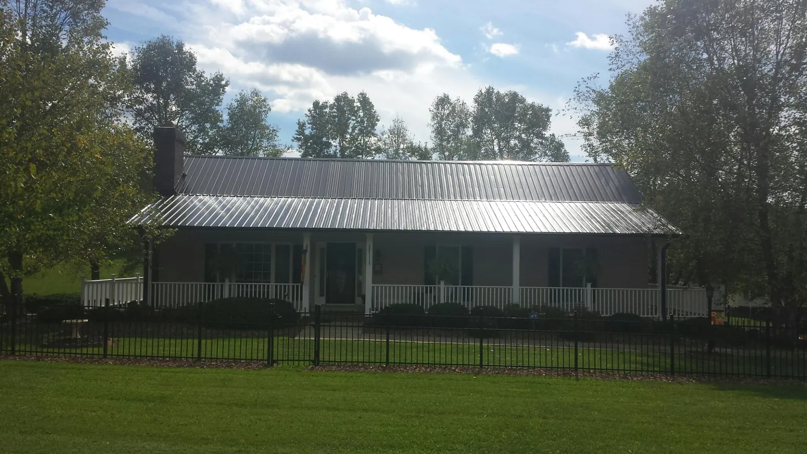 Gray metal roof on a brick ranch with a full width front porch — Gutter Guard Installation work by our crew in Lake Katrine