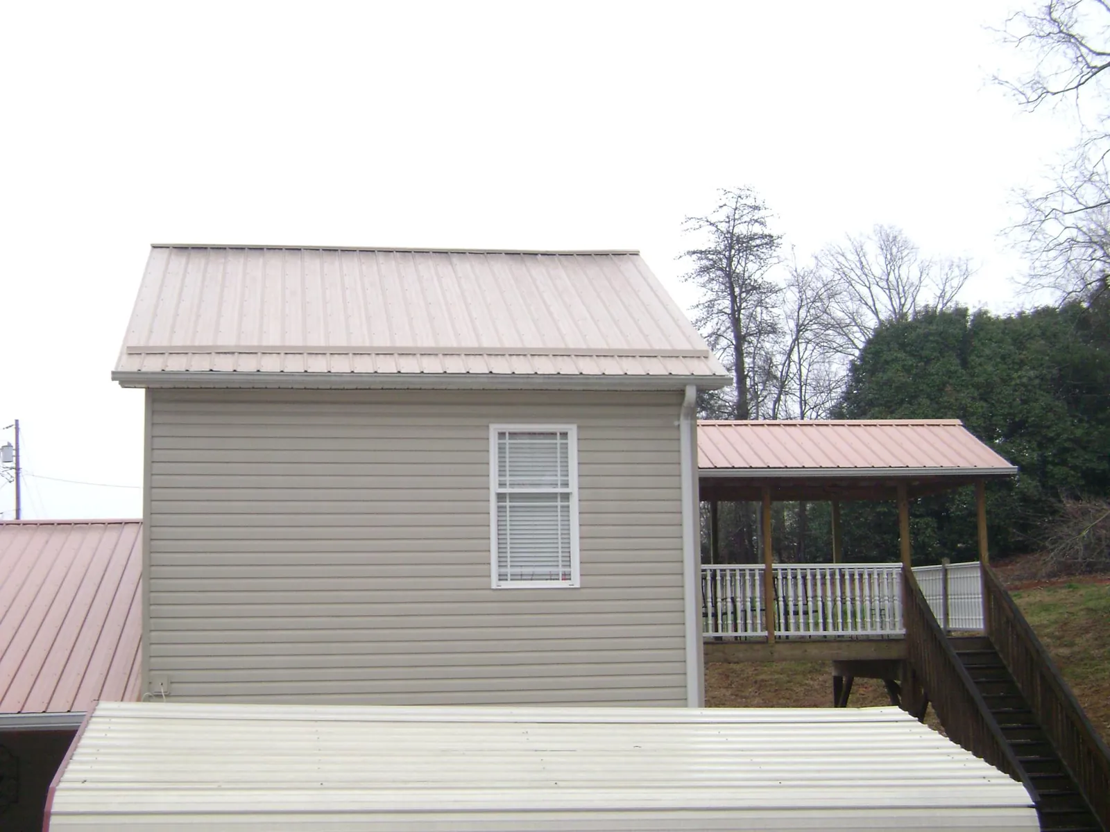 Tan metal roofs on a two story addition and attached porch, from a Roof Replacement job in Lake Katrine