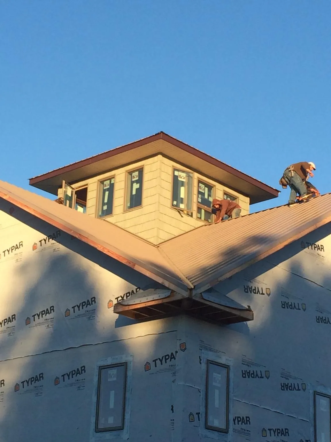 Roofers working around a rooftop cupola on a new metal roof at sunset — Roof Waterproofing in Lake Katrine by Roofing Brothers